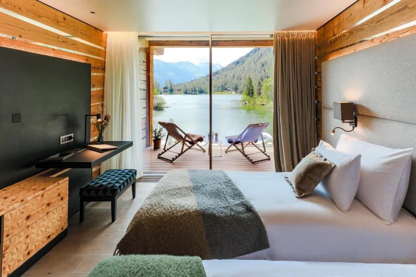 Bedroom with wood accents overlooking a lake and mountains from a private balcony