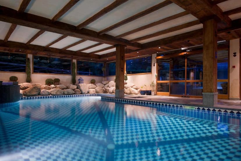 Indoor swimming pool with checkered blue tile floor, wood beams, and rock features, likely Les Grands Montets.