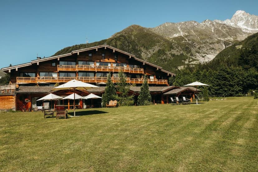 Large wooden chalet hotel with lawn and massive mountains in Les Grands Montets.