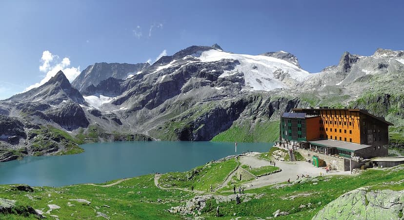 Berghotel Rudolfshütte by turquoise alpine lake below snow-capped mountains