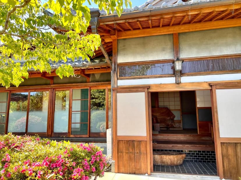 Entrance to NONAGASE GUEST HOUSE with bright pink flowers and traditional wooden architecture.
