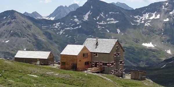 Salmhütte mountain hut with wooden deck against rocky, snow-dusted alpine peaks
