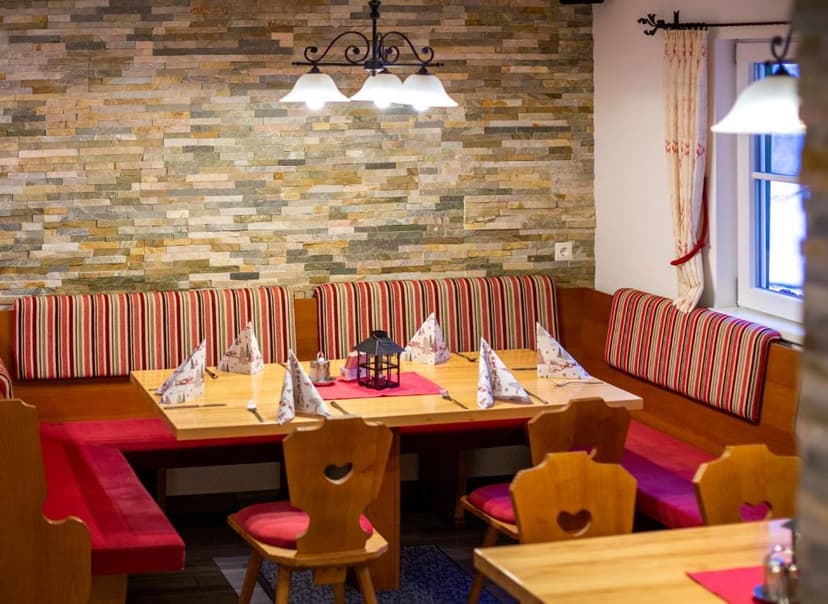 Cozy restaurant dining area with wooden tables, striped bench seating, and stone accent wall.