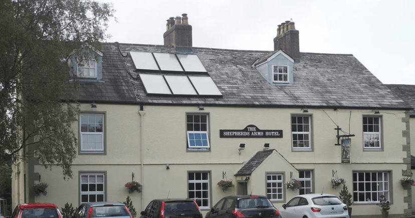 The Shepherds Arms Hotel building with solar panels on the slate roof and parked cars below.