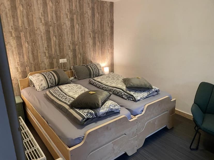 Twin beds with patterned bedding in a room featuring wood-look accent wall and dark floor
