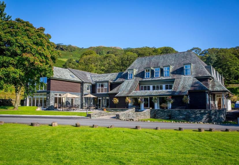 Glaramara Hotel with slate roof set against green fells under a clear blue sky.