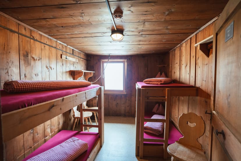 Bunk room with wood paneling, red mattresses, and gingham pillows at Bremer Hütte.