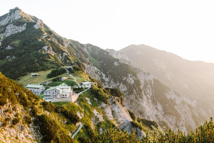 Stripsenjochhaus mountain hut nestled on a steep, green alpine slope at sunrise or sunset.