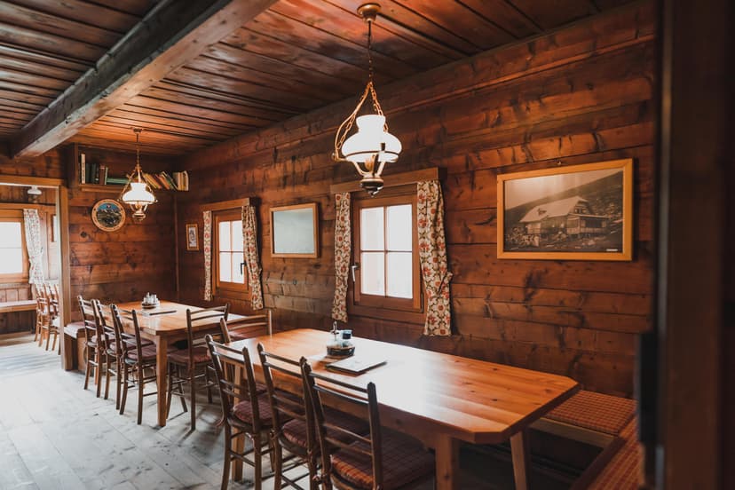 Interior dining room of Millstätter Hütte with wood paneling, tables, and hanging lamps.