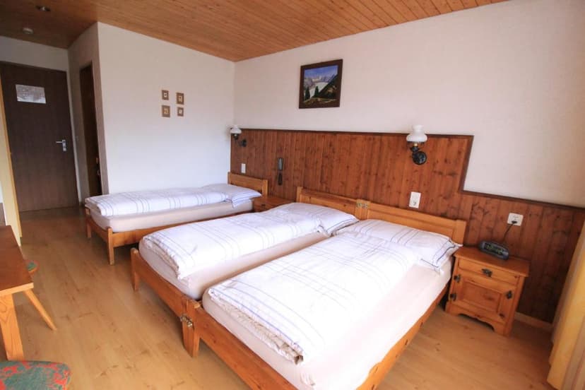 Triple bedroom in Hotel Fiescherhof with wooden accents and white bedding
