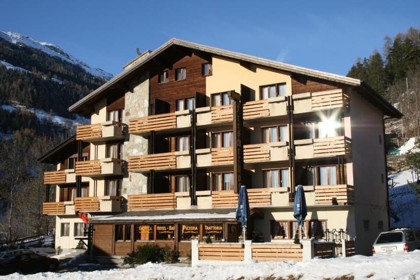 Hotel Fiescherhof with balconies in a snowy alpine setting under a clear blue sky.