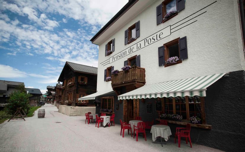 Pension de la Poste building with outdoor seating and striped awning on a village street