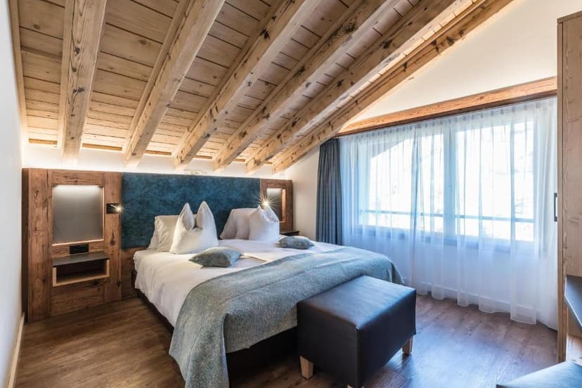 Hotel bedroom with vaulted wooden ceiling, large window, and modern wood accents.