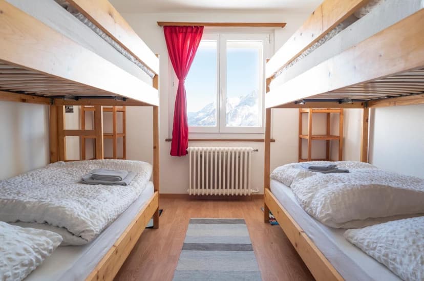 Bunk beds in a room with a window view of snow-capped mountains, Hotel Schwarzsee.
