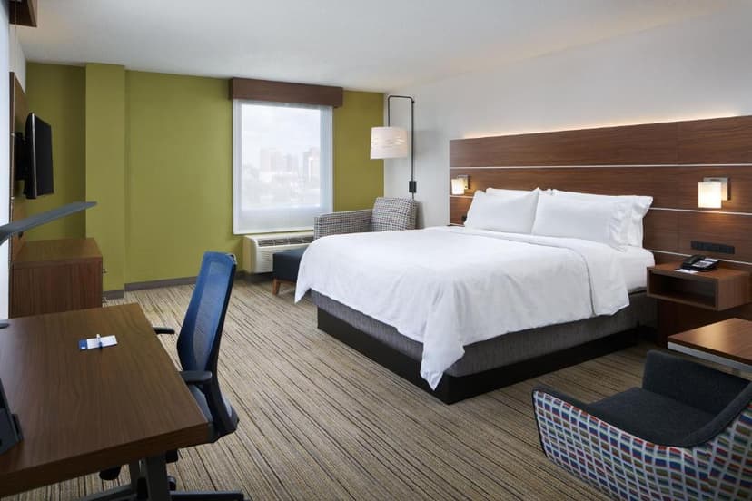 Holiday Inn Express hotel room with king bed, desk, and city view through window
