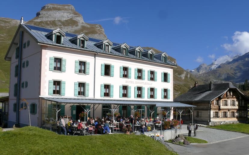 Hotel Engstlenalp with outdoor dining patio against rugged, snow-capped alpine mountains.