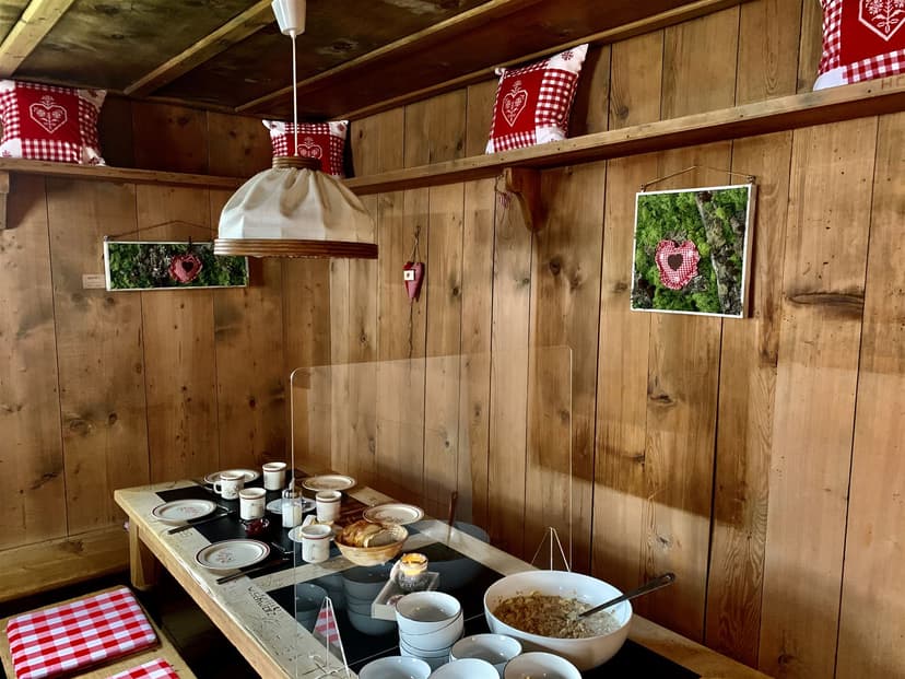 Breakfast spread on wooden table inside Calandahütte with rustic decor and heart motifs.