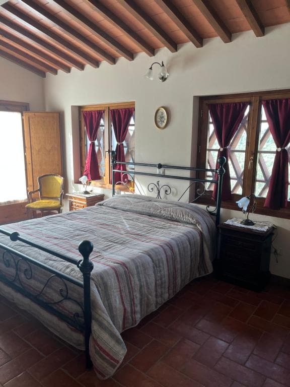 Bedroom with wrought iron bed, terracotta floors, and exposed wooden ceiling beams