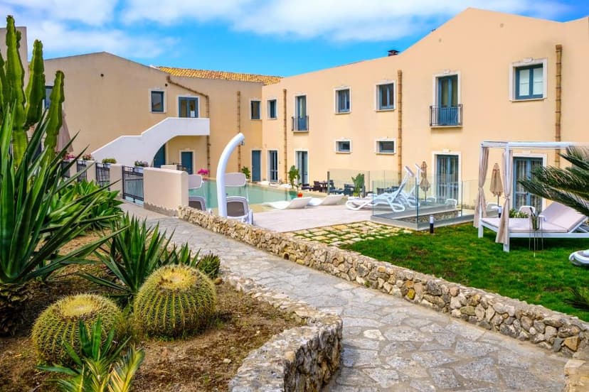 Resort courtyard with pool, lounge chairs, and desert plants under blue sky