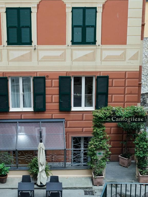 Restaurant entrance "La Camogliese" with ivy archway on rust-colored building in Camogli.