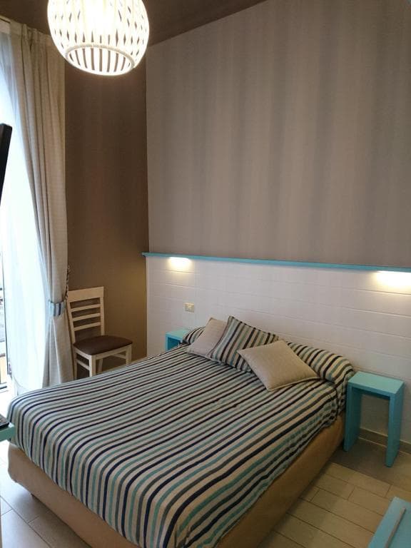 Bedroom with striped blue bedding, white headboard, and bright blue side tables.
