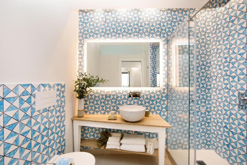 Bathroom vanity with vessel sink, illuminated mirror, and blue geometric tiles, Sorrento style.