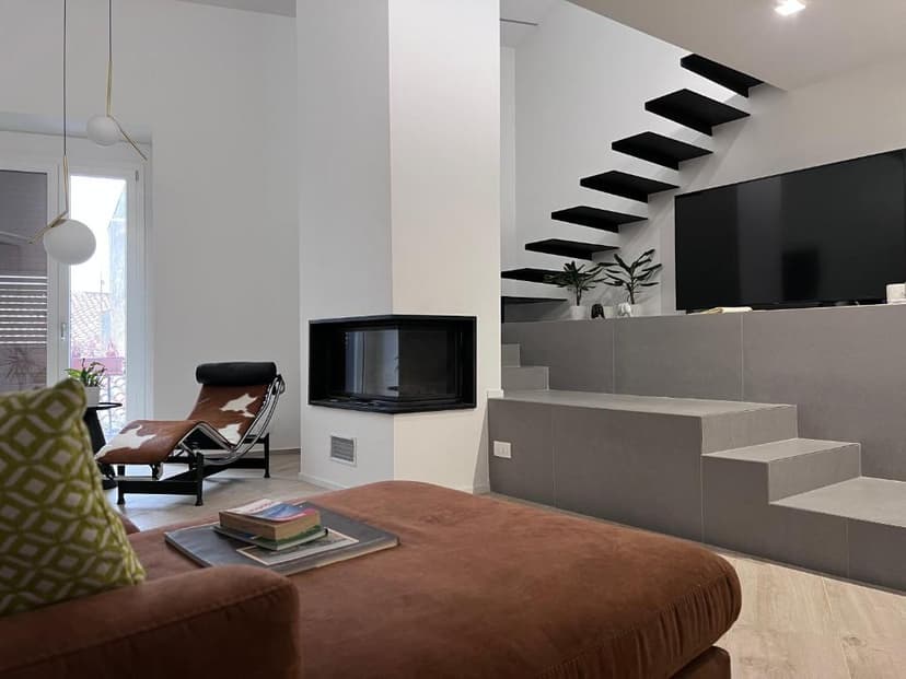 Modern living room with floating black stairs, built-in gray steps, fireplace, and cowhide lounge chair.