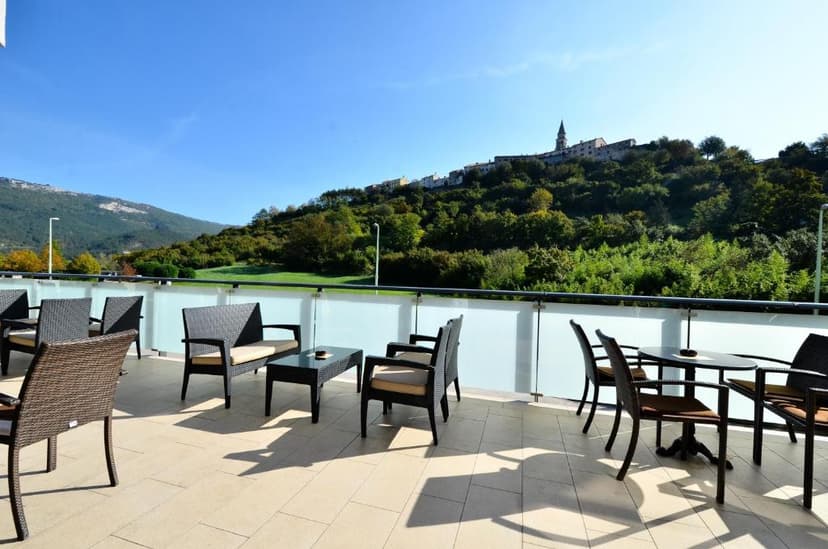 Outdoor patio seating with view of hillside town and mountains under blue sky