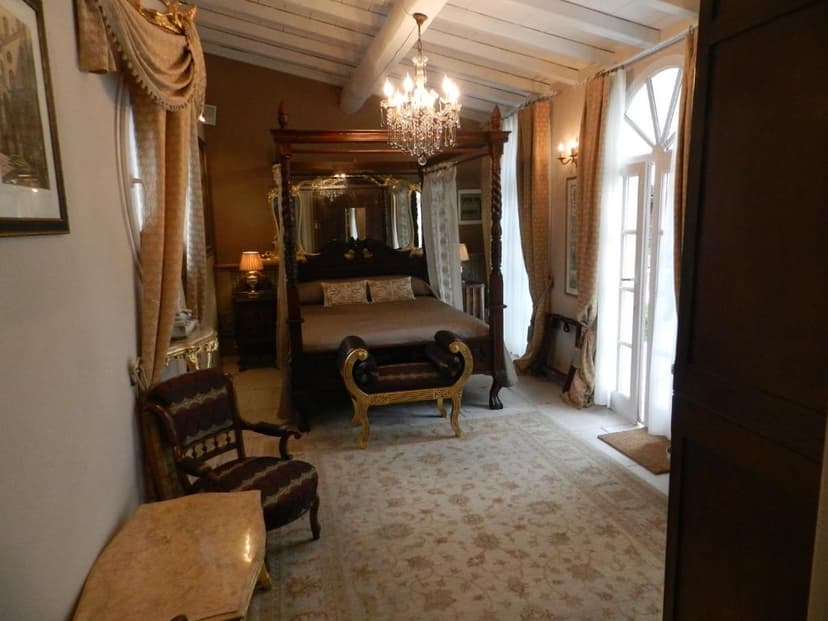 Luxurious bedroom with four-poster bed, chandelier, and balcony doors in Villa Bertagni.