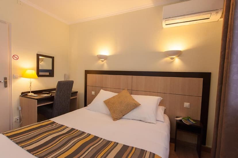 Hotel room with double bed, desk, chair, and wall-mounted air conditioner