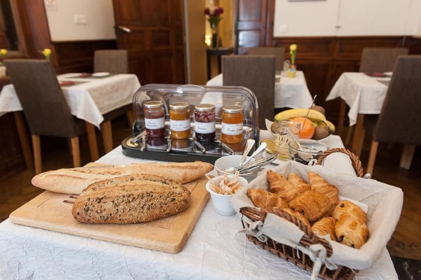 Breakfast spread with baguettes, croissants, jams, and fruit in a dining room setting