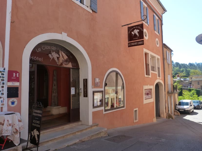 Hotel Le Clos de la Glycine with Restaurant David entrance on narrow street with parked cars.