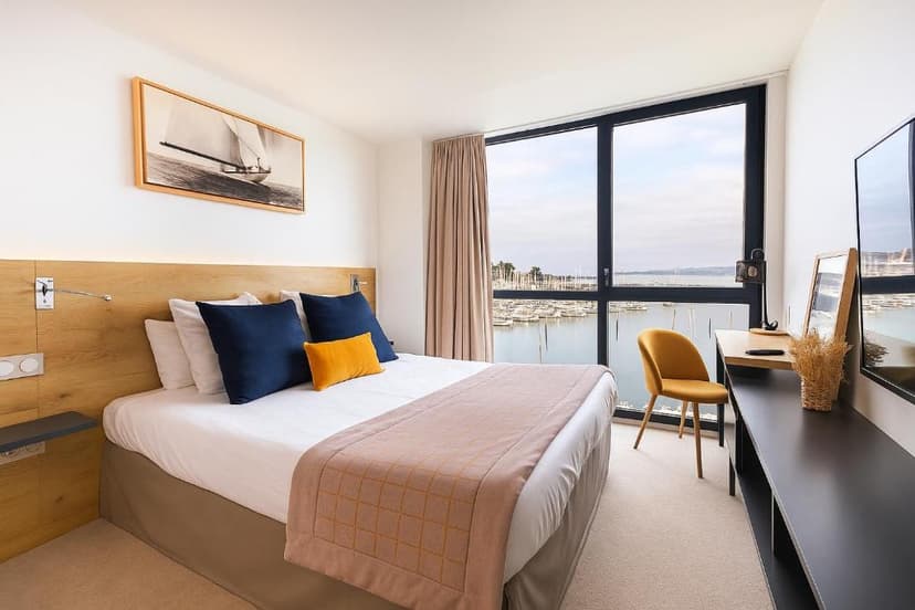 Hotel room with bed and large window view of a marina filled with boats