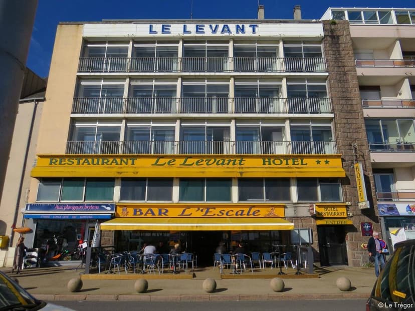 Le Levant Hotel and Restaurant building with yellow awnings and outdoor cafe seating.