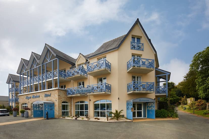 Hotel Aigue Marine with beige facade and blue balconies under a cloudy sky