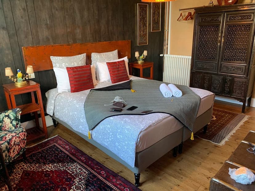 Hotel room with double bed, dark wood walls, and antique Asian-style wardrobe.