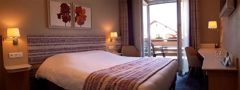 Hotel room with large bed, artwork, and balcony access at Hôtel les Remparts.