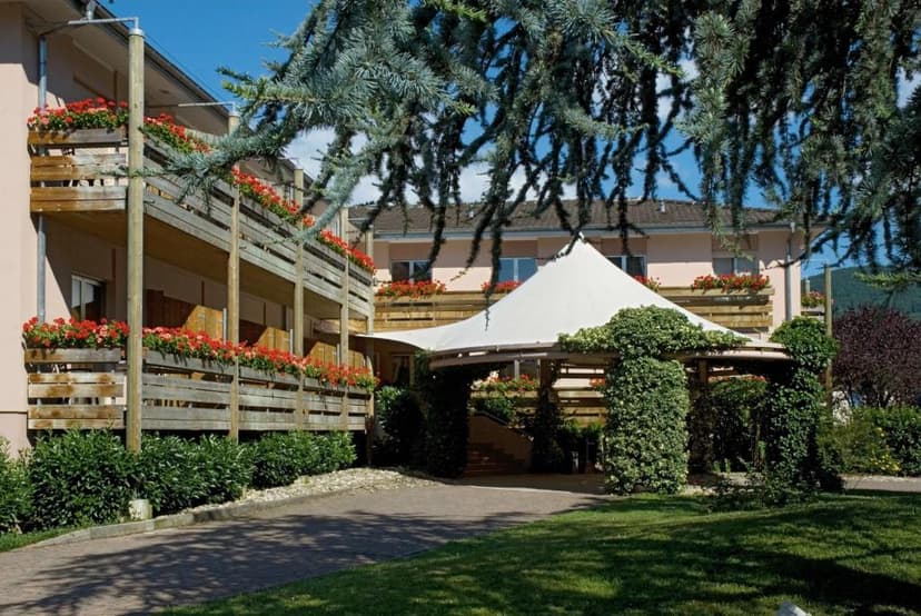Hotel Les Remparts entrance with wooden balconies, red flowers, and ivy-covered canopy