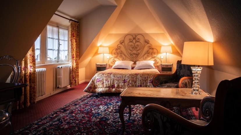 Attic hotel bedroom with ornate metal headboard, patterned bedding, and warm lighting at Hôtel-des-Deux-Clefs.