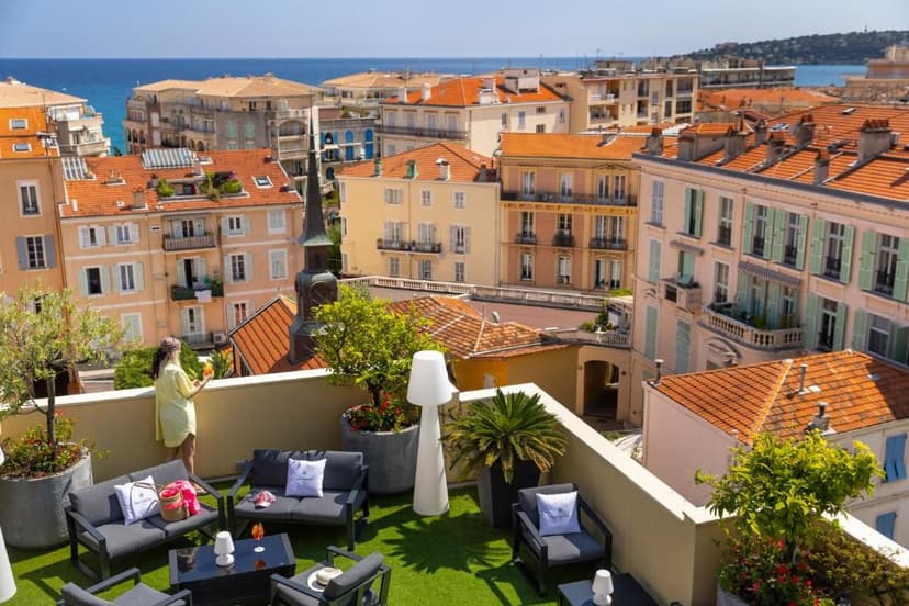 Rooftop terrace overlooking Mediterranean coastal town with orange tile roofs and sea view