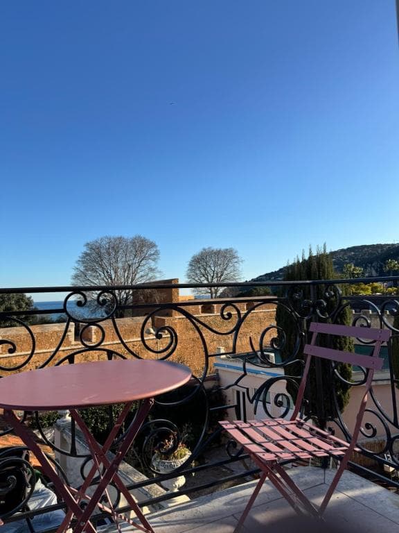 Balcony with wrought iron railing, table, and chair overlooking the sea near Hotel La Citadelle.