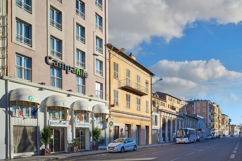 Campanile hotel exterior on a street with parked cars and a bus under a blue sky.