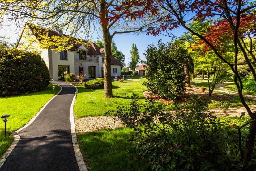 House with lush green garden and paved walkway near Mont Saint-Michel.
