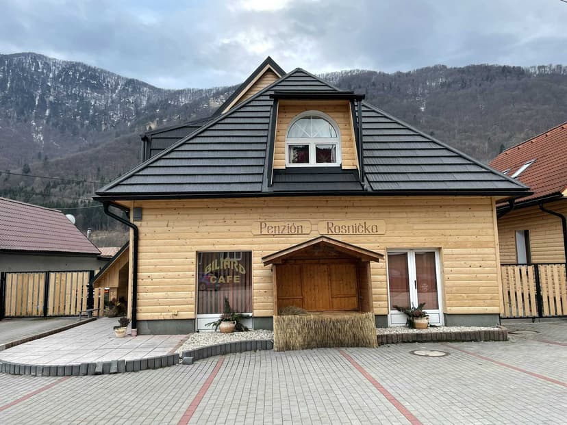 Penzión Rosnička wooden building with snow-dusted mountains in background