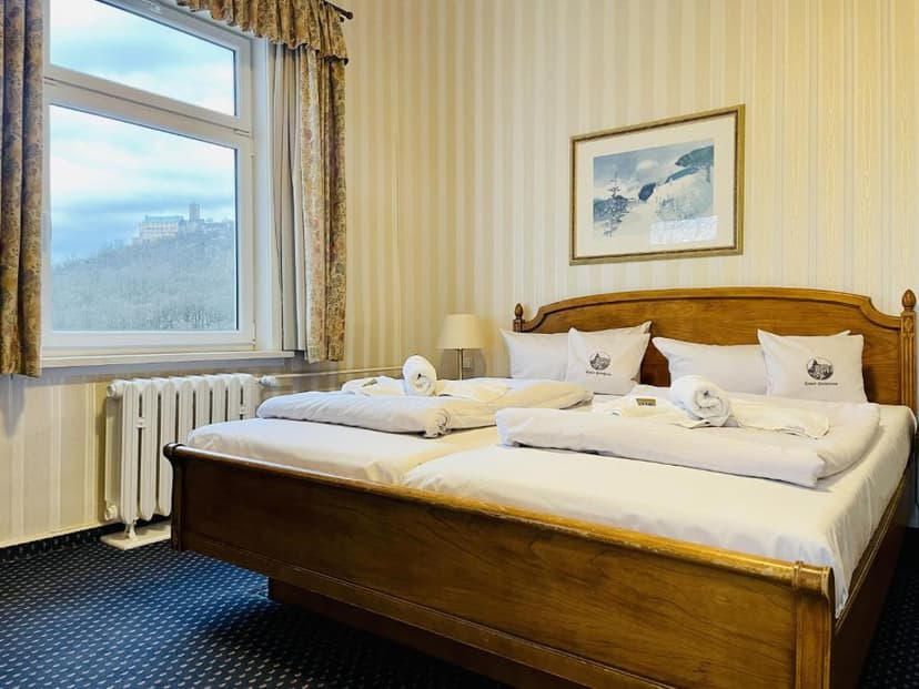 Hotel room with wooden bed, view of a castle on a hill through the window.