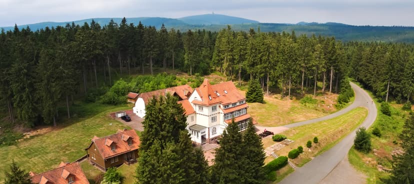 Spießberghaus hotel nestled in dense pine forest with distant mountain view