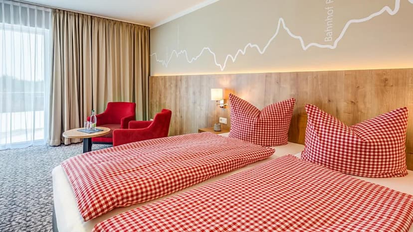 Twin hotel room with red gingham bedding, wood headboard, and mountain graphic art