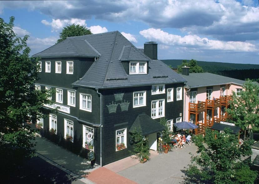Hotel building with dark slate siding and outdoor dining area surrounded by green hills.