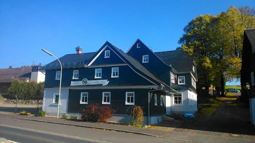 Antikhotel Steinbacher Hof building with dark siding and white trim under a clear blue sky.