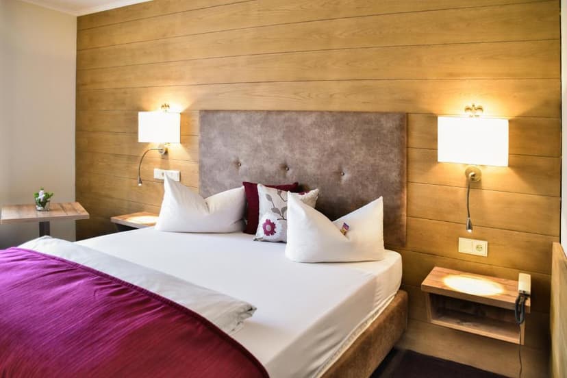 Bedroom with wood paneling, white bedding, and a magenta throw, likely in Gästehaus am Kurpark.